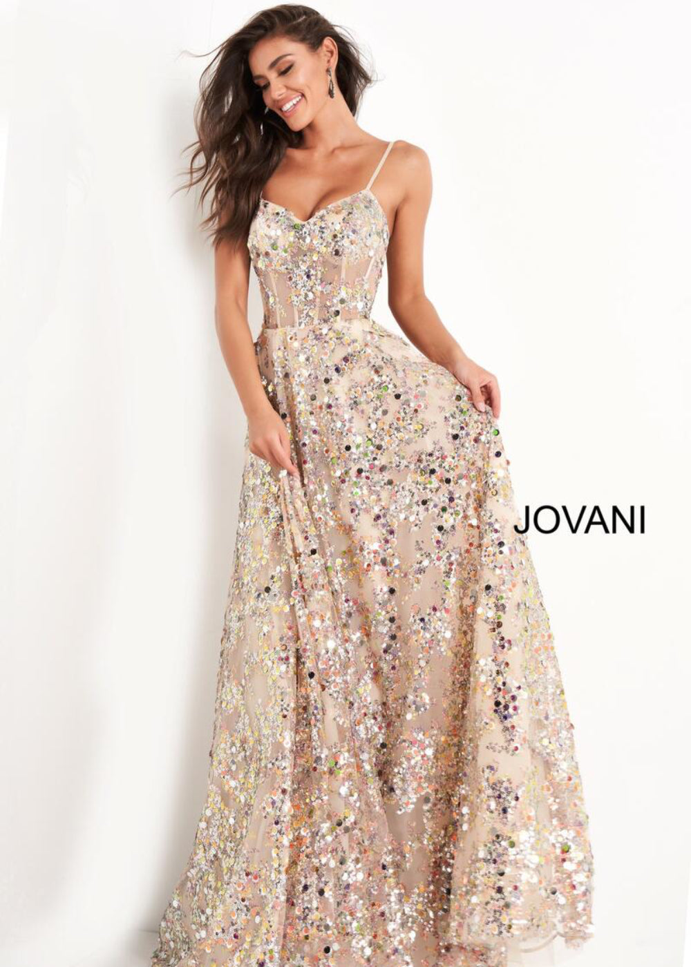 A woman wearing a beige, sequined Jovani dress with a deep v-neckline and spaghetti straps.