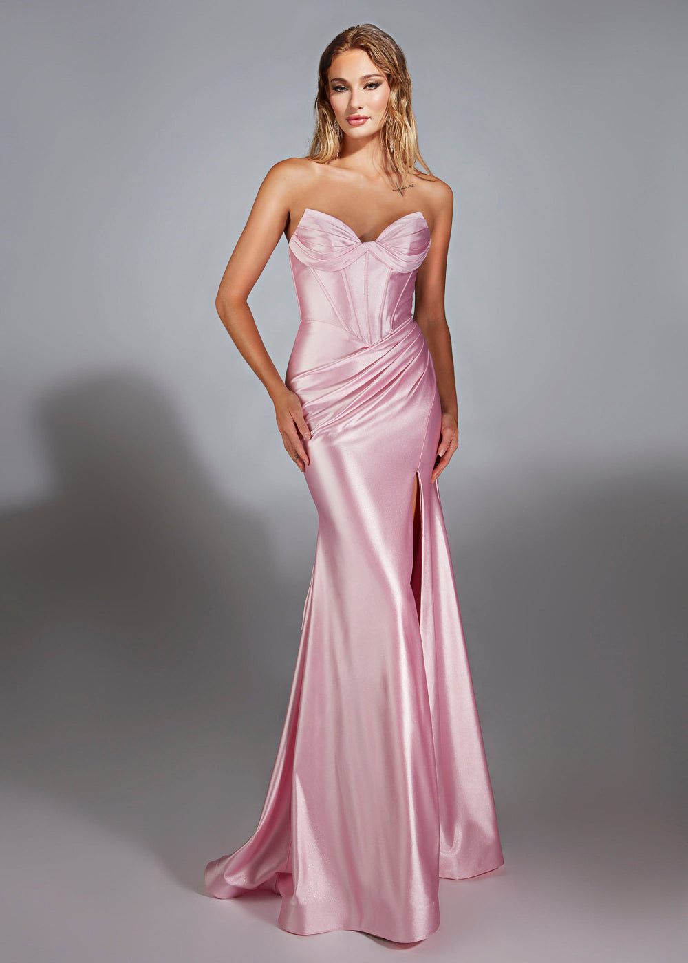 A woman wearing a pink, strapless, formal evening gown with a sweetheart neckline and a maxi skirt.