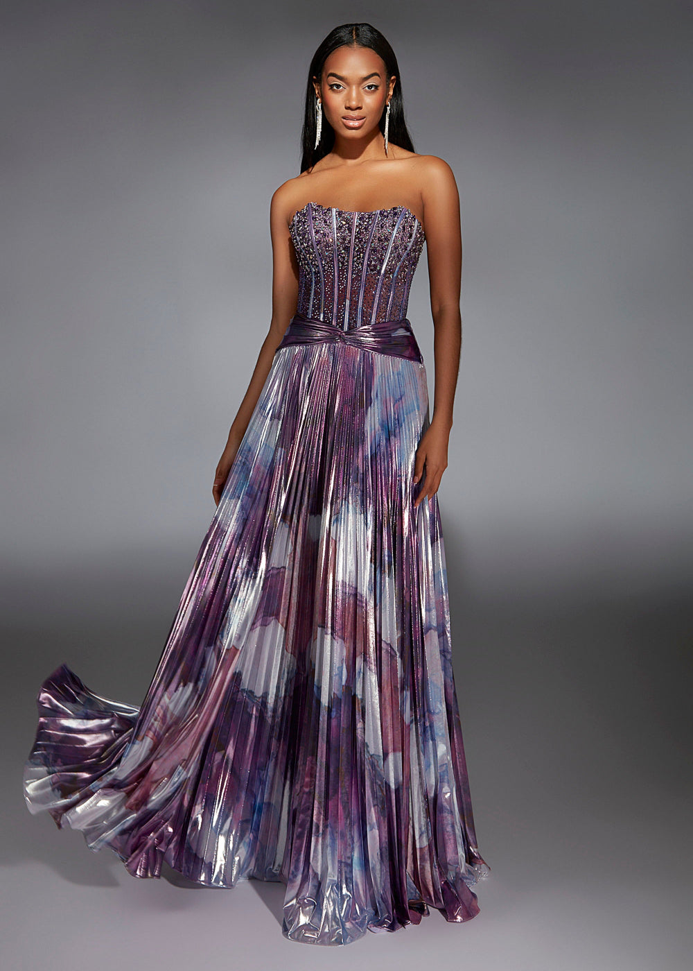 A woman wearing a long, pleated, multicolored formal dress with a sweetheart neckline.