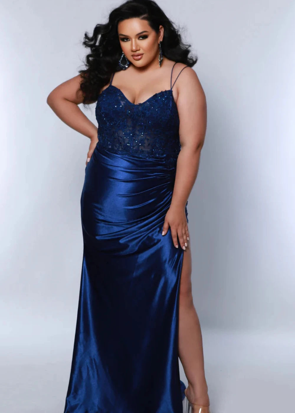 Woman wearing a blue satin evening gown with a slit on a white background
