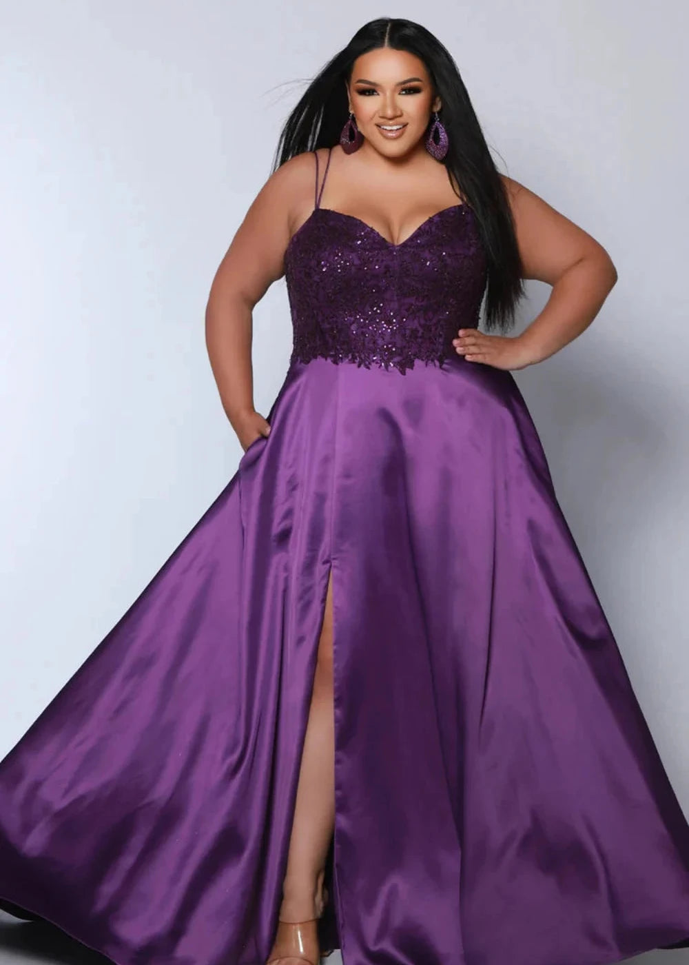 Woman wearing a purple evening gown with a slit on a white background