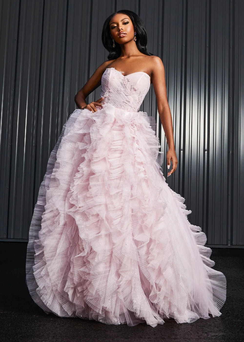 A woman wearing a pink strapless, ruffled, full-length dress with a sweetheart neckline.